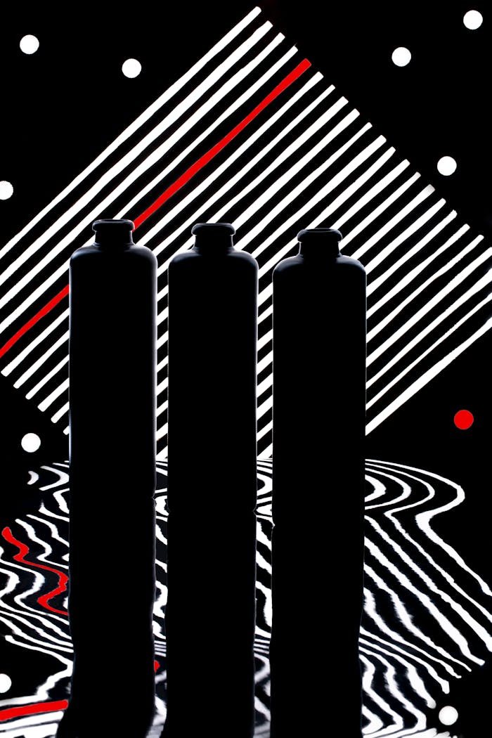 Artistic photo of three silhouetted bottles with abstract patterns.