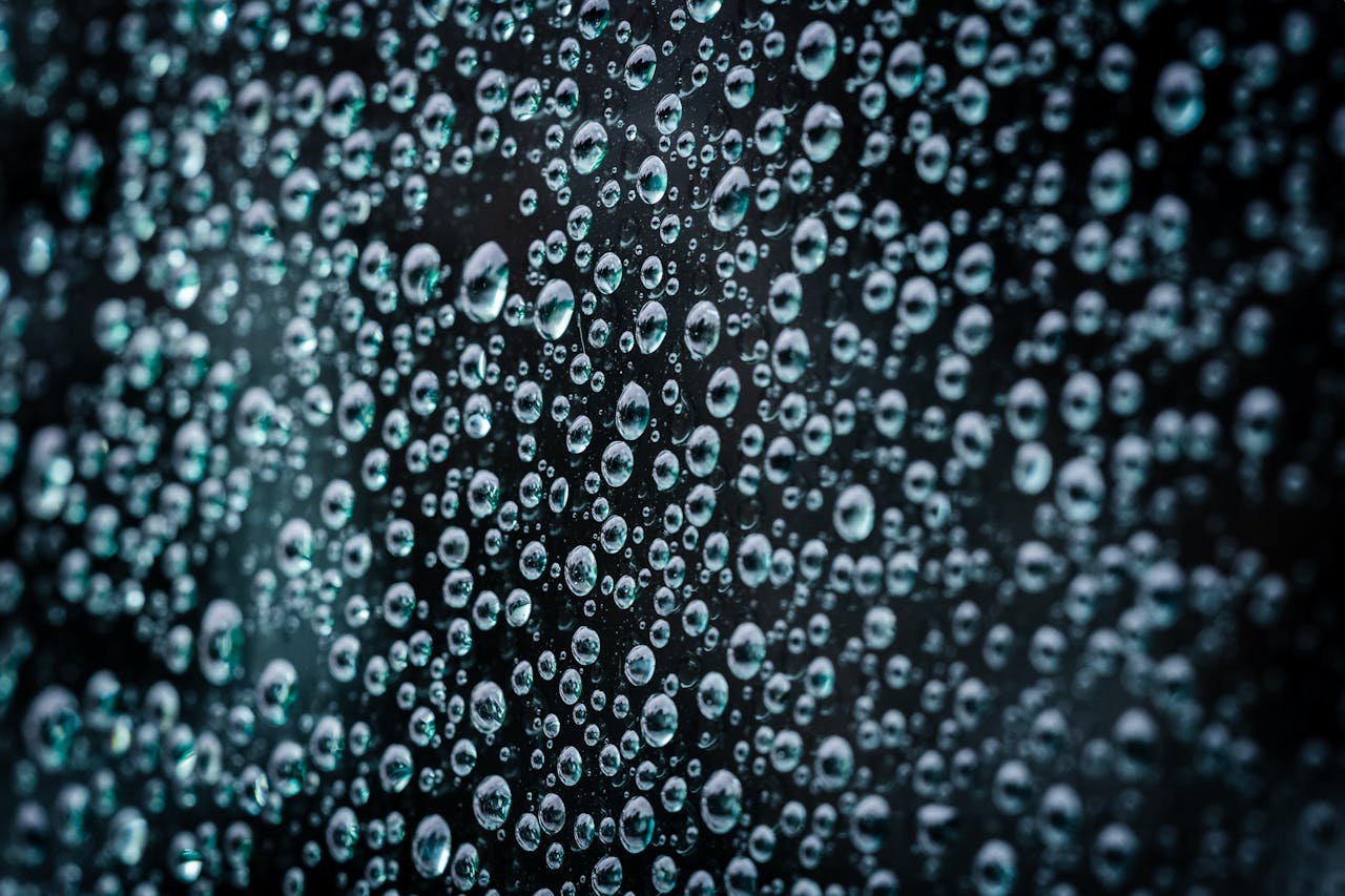 Close-up macro photograph of water droplets on a glass surface creating a textured pattern.